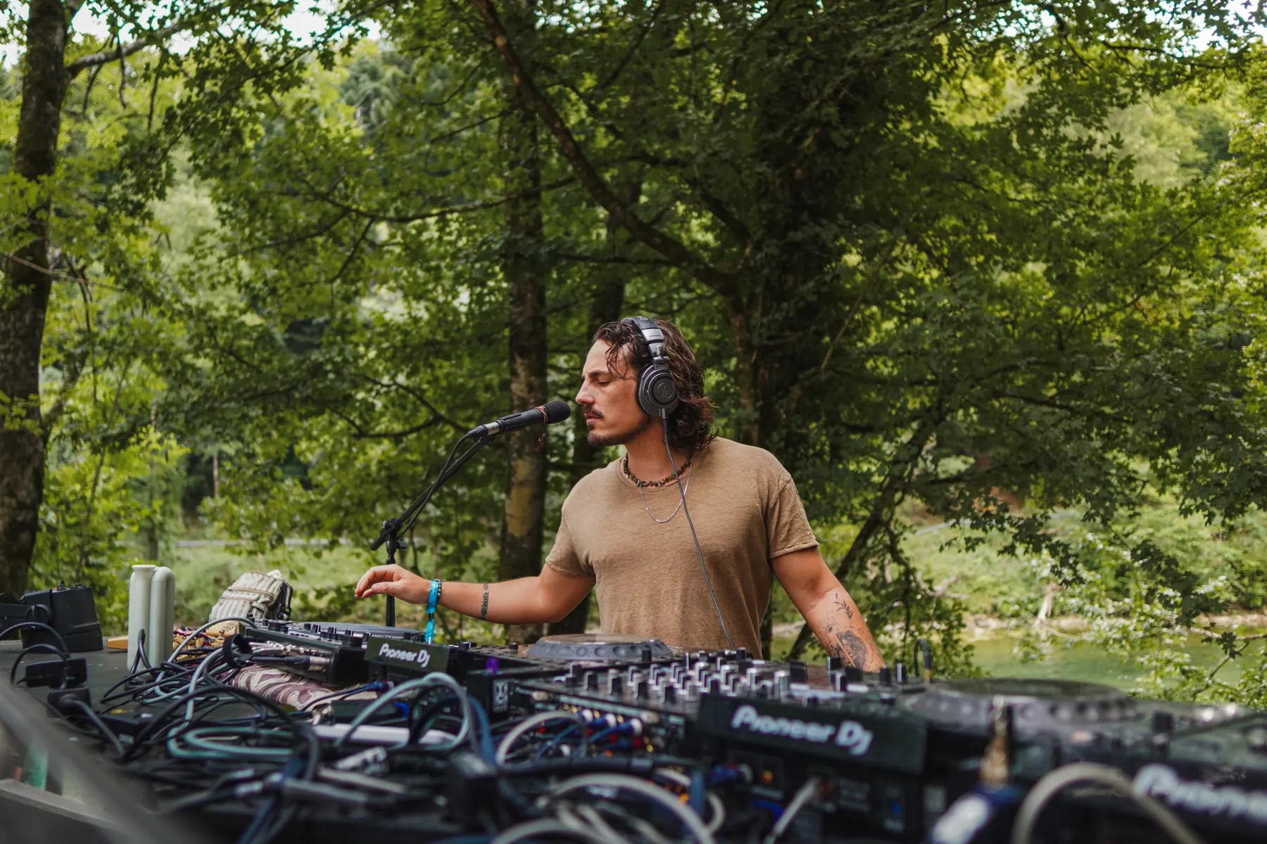 Jasileo singing behind the decks in a forest